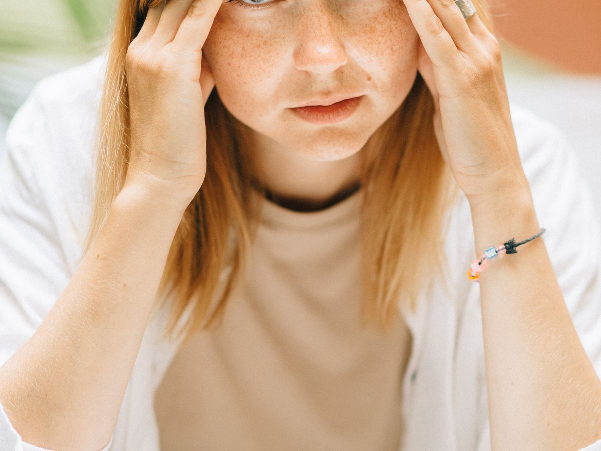 Woman looking stressed, with her hands on her temples
